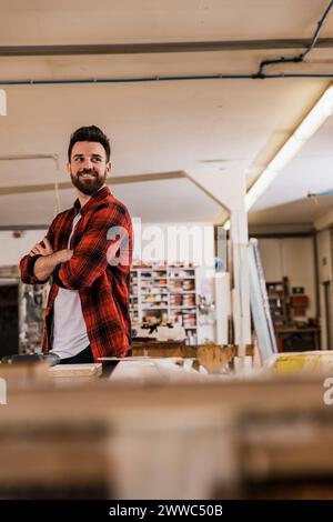 Smiling carpenter standing with arms crossed at workshop Stock Photo