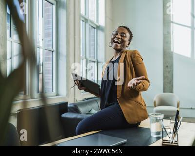 Cheerful businesswoman with tablet PC sitting at desk in office Stock Photo