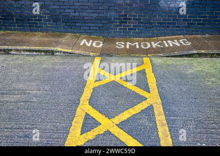 No Smoking warning painted on pavement next to parking space Stock Photo