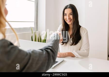 Smiling recruiter shaking hands with candidate at office Stock Photo