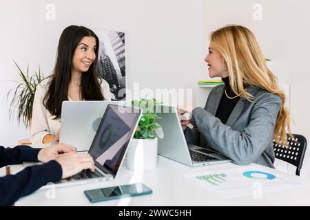 Happy businesswomen having discussion at desk in office Stock Photo