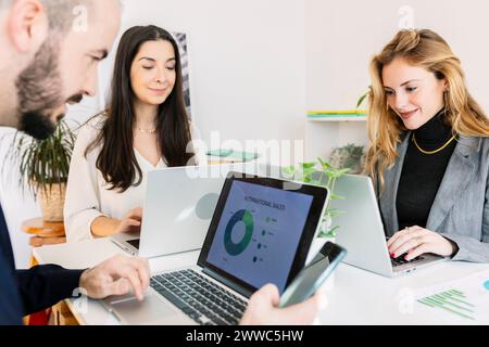Business people working on laptop and discussing in office Stock Photo