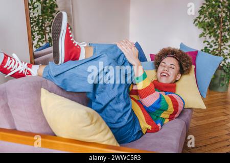 Smiling young woman lying on sofa at home Stock Photo