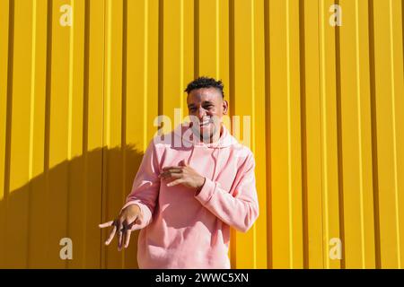 Cheerful young man having fun in front of yellow wall Stock Photo