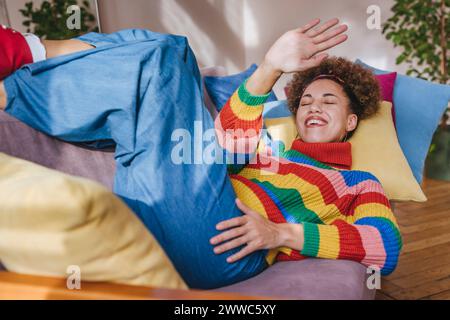 Happy woman shielding eyes on sofa at home Stock Photo