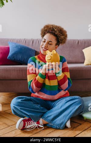 Happy young woman sitting with piggy bank Stock Photo