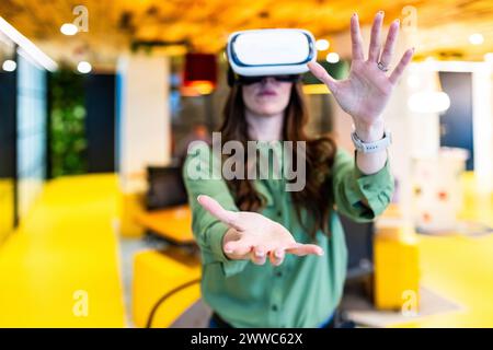 Businesswoman using virtual reality simulator and gesturing in office Stock Photo