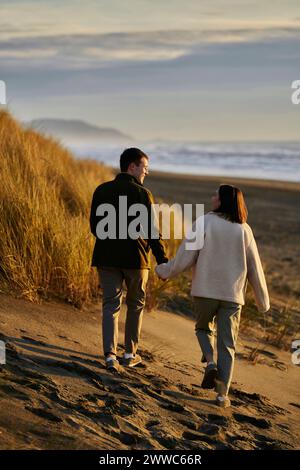 Young man and woman holding hands at beach Stock Photo