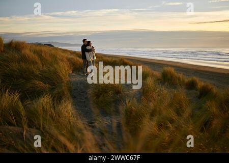 Young man embracing girlfriend at beach Stock Photo