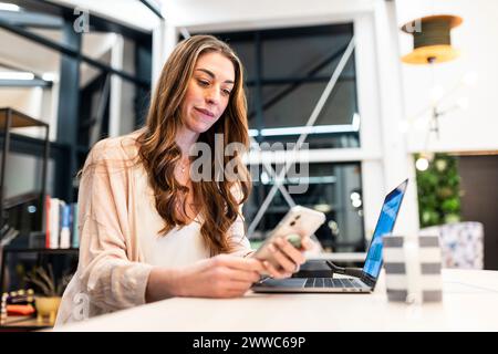 Mature businesswoman using smart phone at desk in office Stock Photo