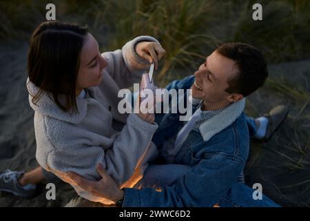 Happy man looking at girlfriend taking out photographic print from camera at beach Stock Photo