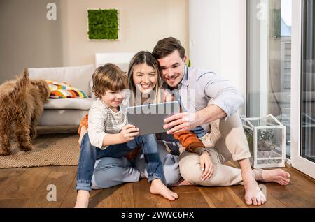 Happy family using tablet PC and sitting in living room at home Stock Photo