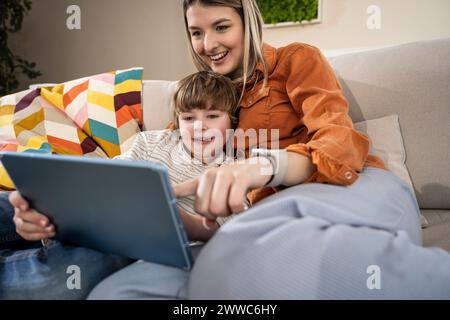 Happy boy with mother using tablet PC at home Stock Photo