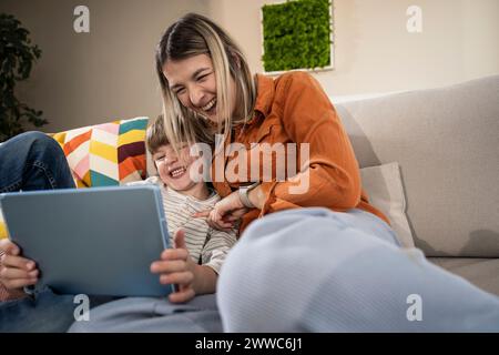 Cheerful boy with mother using tablet PC at home Stock Photo