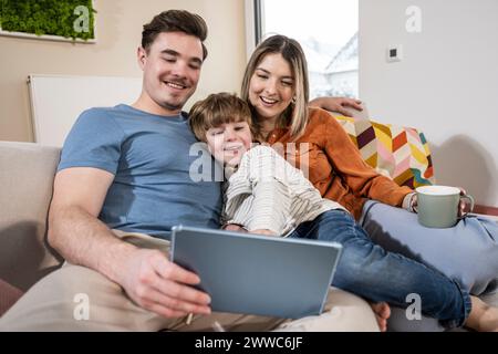 Happy family using tablet PC on sofa at home Stock Photo