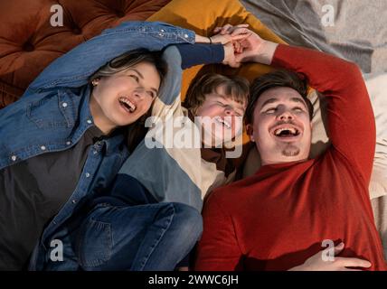 Cheerful family holding hands and enjoying on bed at home Stock Photo