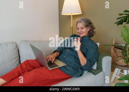 Smiling freelancer with reminder knot on finger using laptop at home office Stock Photo