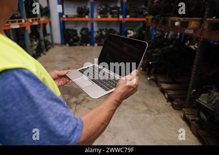 Senior auto mechanic holding laptop at warehouse Stock Photo