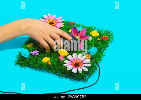 Businesswoman holding computer mouse on flowerbed against blue background Stock Photo