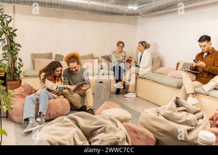 Diverse business colleagues using wireless technologies and talking on break at office Stock Photo