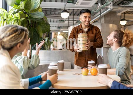 Smiling businessman holding stack of containers at lunch break in office Stock Photo