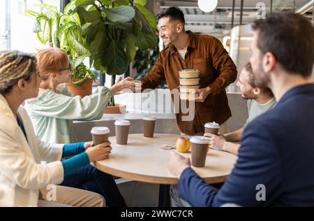 Businessman serving food to colleagues at lunch break in office Stock Photo