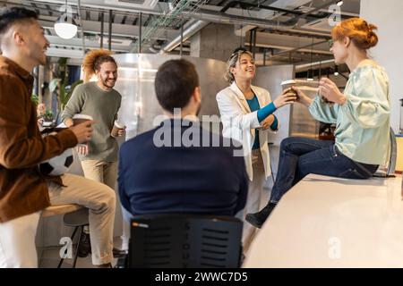 Happy businesswoman serving coffee to colleagues at office cafe Stock Photo