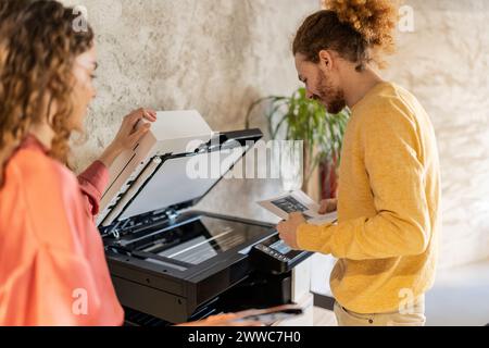 Businessman using photocopier machine with colleague at office Stock Photo