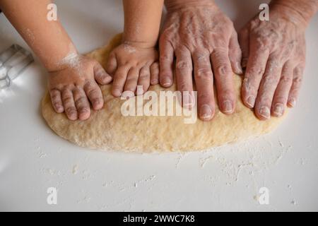 Hands of grandmother and grandson kneading dough at home Stock Photo