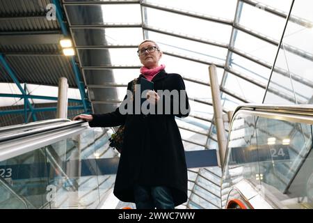 Businesswoman moving down on escalators at station Stock Photo