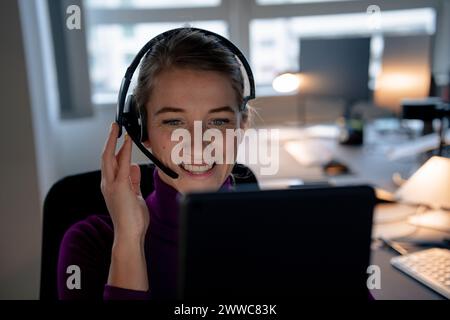 Happy customer service representative wearing headset and talking in office Stock Photo