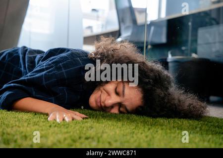 Smiling businesswoman resting on carpet in office Stock Photo