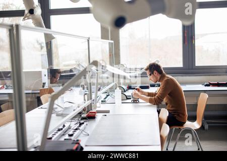 Mature engineer sitting on chair and working at workshop Stock Photo