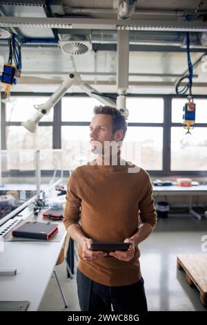 Thoughtful engineer holding tablet PC Stock Photo
