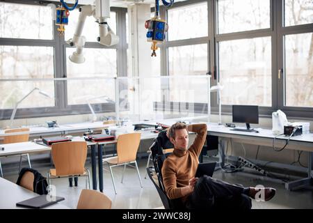 Engineer using tablet PC sitting on chair at workshop Stock Photo