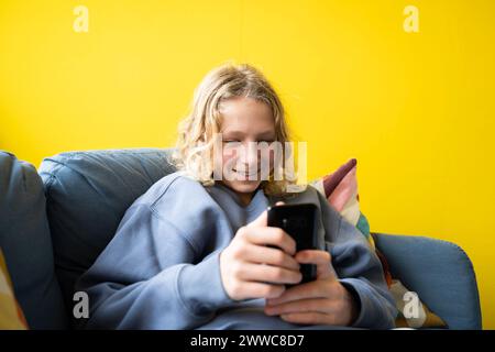Smiling boy using smart phone at home Stock Photo