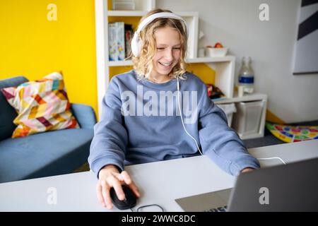 Happy boy playing video game on laptop at home Stock Photo