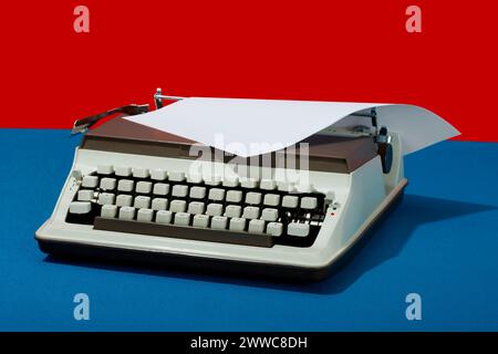 Retro typewriter with paper against colored background Stock Photo