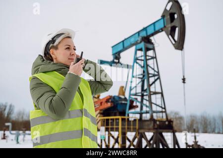 Engineer wearing hardhat and talking on walkie-talkie at oil field Stock Photo