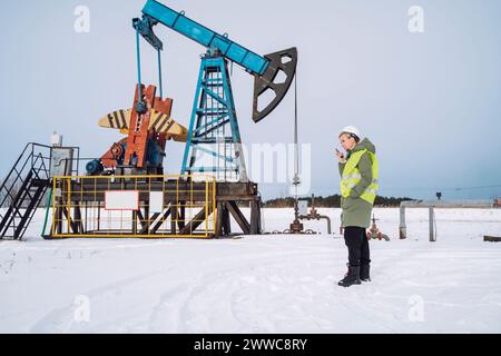 Engineer talking on walkie-talkie at oil field in winter Stock Photo