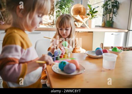 Sisters painting Easter eggs at home Stock Photo