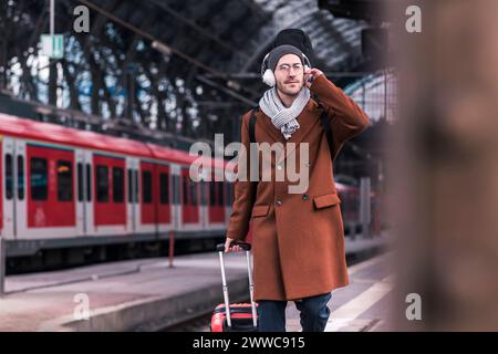 Businessman wearing wireless headphones and walking on platform Stock Photo