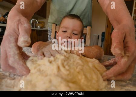 Grandmother and grandson kneading dough on table in kitchen at home Stock Photo