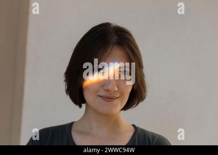 Smiling woman with multi-colored light on face Stock Photo