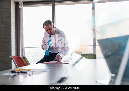 Senior businessman with coffee cup in meeting room at office Stock Photo