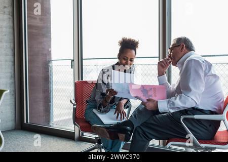 Multiracial business colleagues discussing over documents at workplace Stock Photo