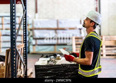 Worker examining and holding documents at warehouse Stock Photo