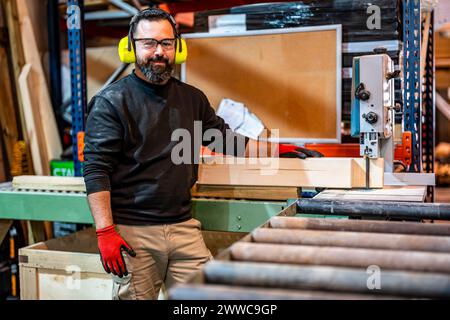 Smiling worker standing near conveyor belt at industry Stock Photo