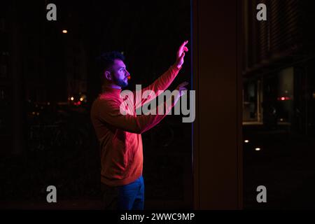 Man using touch screen kiosk machine on street at night Stock Photo