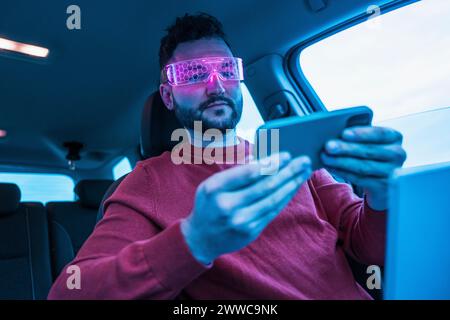 Man wearing pink smart glasses and using mobile phone in car Stock Photo